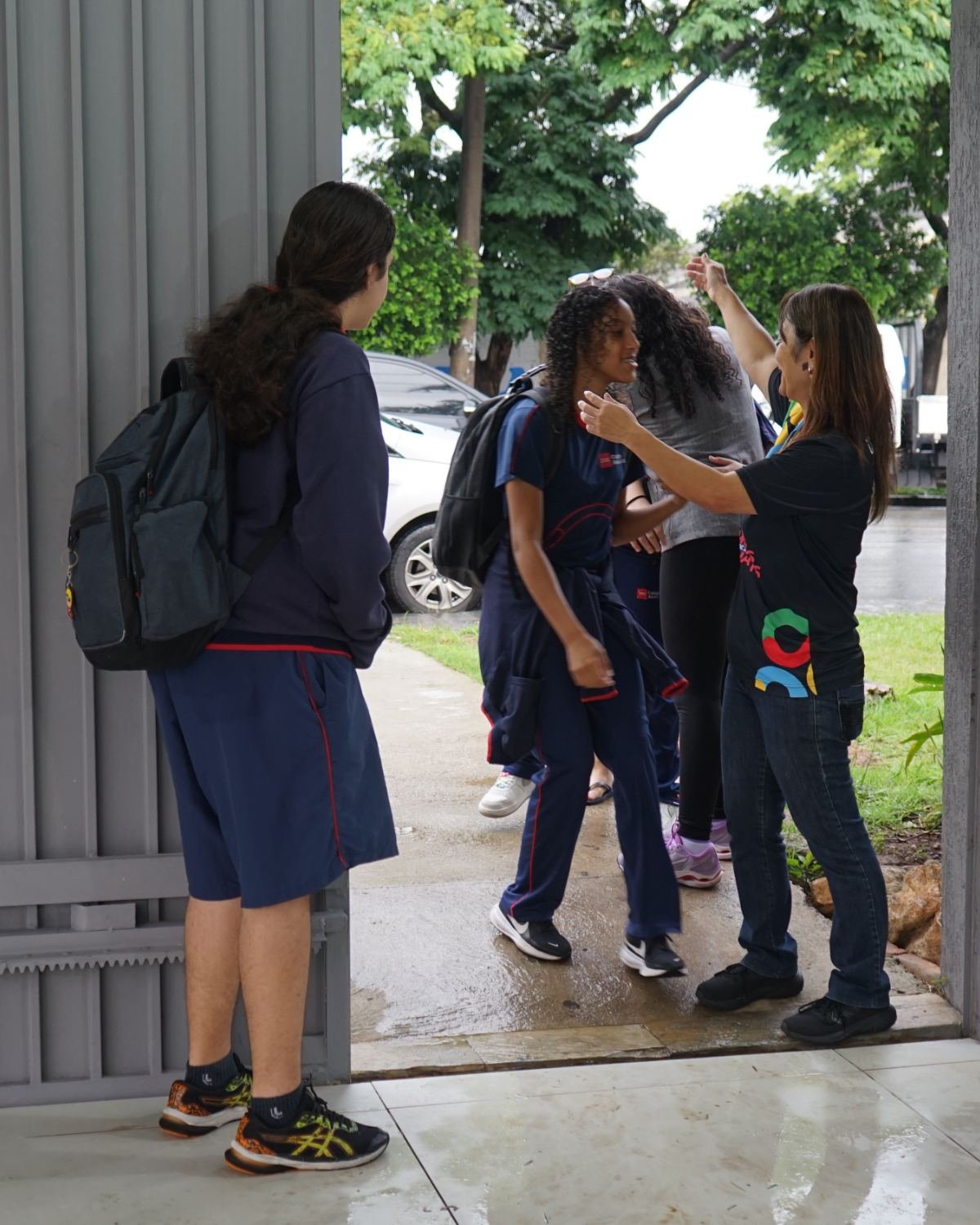 Coordenadora do Colégio Alceu Cotta acolhendo alunos na entrada da escola.